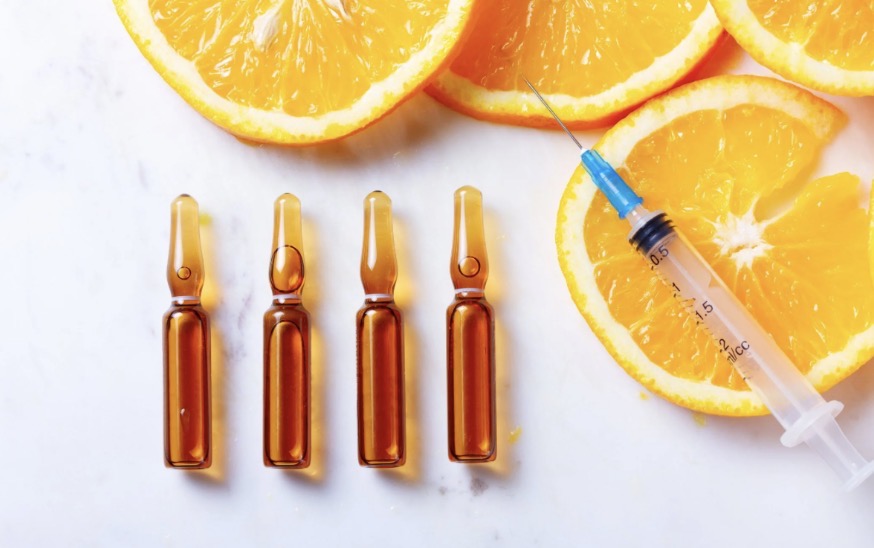Vitamin ampoules and syringe with fresh oranges